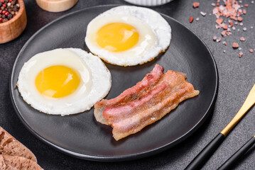 English breakfast with fried eggs, bacon, beans, tomatoes, spices and herbs