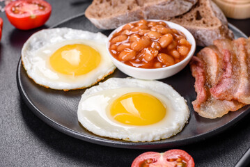 English breakfast with fried eggs, bacon, beans, tomatoes, spices and herbs