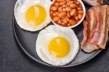 English breakfast with fried eggs, bacon, beans, tomatoes, spices and herbs