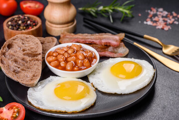 English breakfast with fried eggs, bacon, beans, tomatoes, spices and herbs