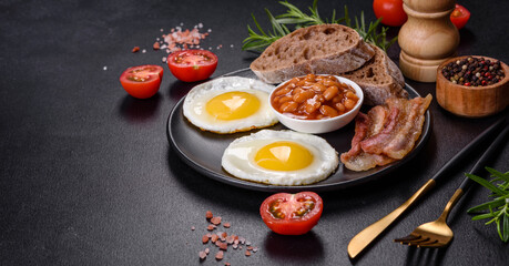 English breakfast with fried eggs, bacon, beans, tomatoes, spices and herbs