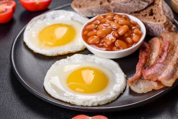 English breakfast with fried eggs, bacon, beans, tomatoes, spices and herbs