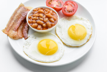 English breakfast with fried eggs, bacon, beans, tomatoes, spices and herbs