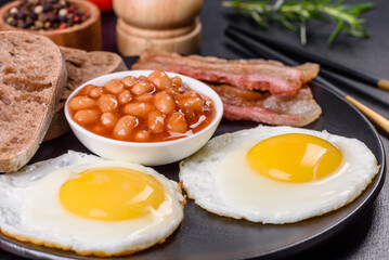 English breakfast with fried eggs, bacon, beans, tomatoes, spices and herbs