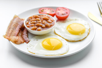 English breakfast with fried eggs, bacon, beans, tomatoes, spices and herbs
