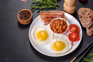 English breakfast with fried eggs, bacon, beans, tomatoes, spices and herbs