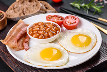 English breakfast with fried eggs, bacon, beans, tomatoes, spices and herbs