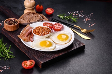English breakfast with fried eggs, bacon, beans, tomatoes, spices and herbs