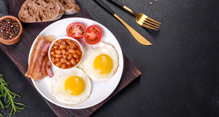 English breakfast with fried eggs, bacon, beans, tomatoes, spices and herbs