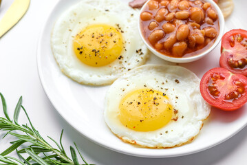 English breakfast with fried eggs, bacon, beans, tomatoes, spices and herbs