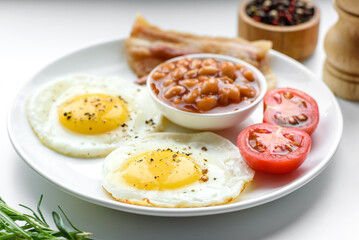 English breakfast with fried eggs, bacon, beans, tomatoes, spices and herbs