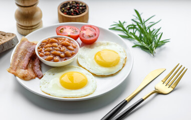 English breakfast with fried eggs, bacon, beans, tomatoes, spices and herbs