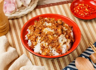 Signature Braised Pork Rice in a bowl with spoon and chopsticks isolated on mat side view on wooden table taiwan food