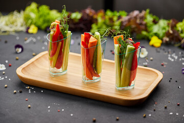 Fototapeta na wymiar Colorful slices of raw vegetables in glasses (carrots, cucumber, sweet pepper). The concept of diet, healthy and vegetarian food.