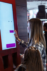 young beautiful woman chooses food and makes an order at the self-service terminal in a cafe