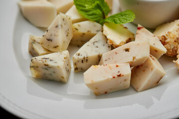 Cheese plate: Parmesan, cheddar, gouda, mozzarella and other with honey on white plate on dark background . Tasty appetizers. Top view. Photo for restaurant menu