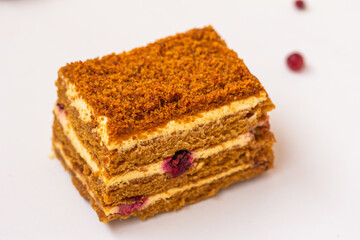 Orange colored cake. A piece of a honey cake with red berries, on white background, isolated, copy space.