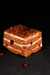 Close up of a tasty cake with cream and red berries on dark background