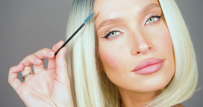Close-up view of a beautiful blonde woman making eyebrow correction.