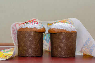 two Easter cakes stand on the table covered with a festive towel
