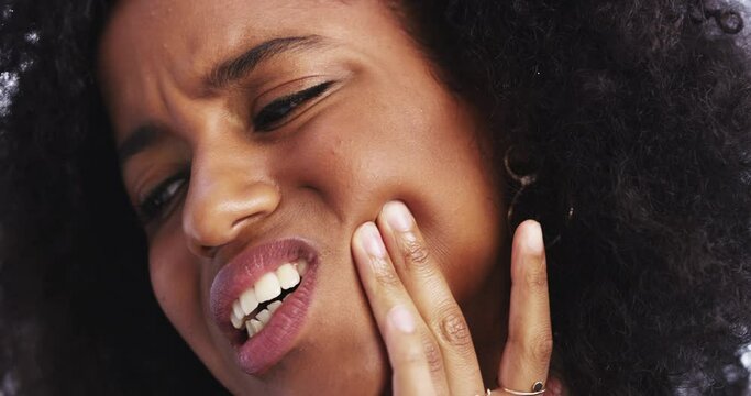 This toothache has been bothering me all day. 4k video footage of a young businesswoman rubbing her jaw in discomfort while in her corporate office.
