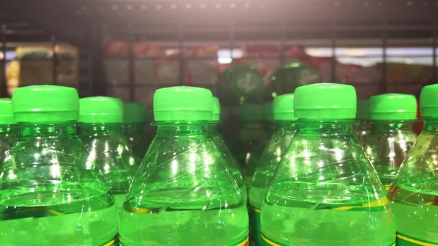 Lemonade in green plastic bottles stand on the shelves of a supermarket or warehouse. Closeup