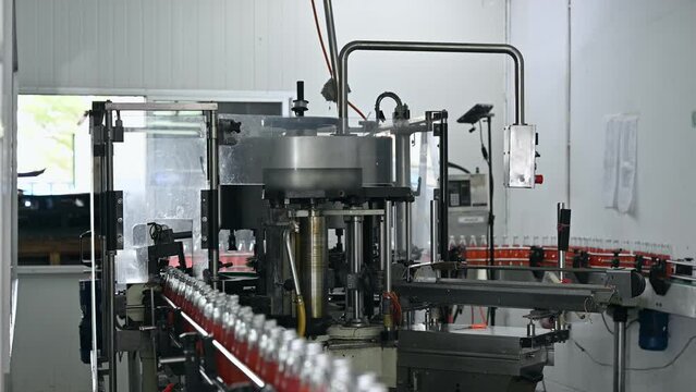 Automatic product labeling machinery working with red juice in production line at bottling factory