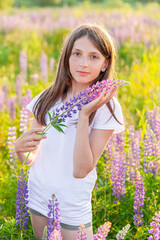 Happy teenage girl smiling outdoor. Beautiful young teen woman resting on summer field with blooming wild flowers green background. Free happy kid teenager girl, childhood concept