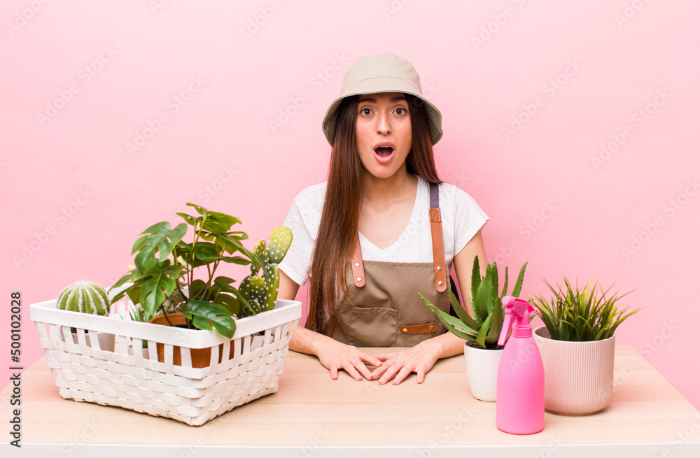 Wall mural hispanic pretty woman looking very shocked or surprised. plants and gardering concept