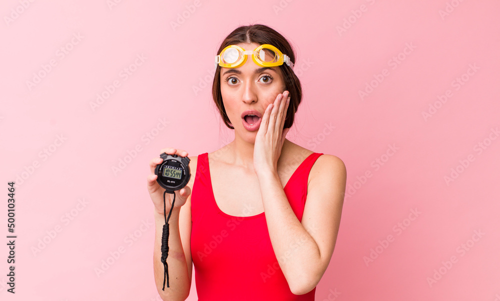 Wall mural hispanic pretty woman feeling shocked and scared. swimmer and timer concept