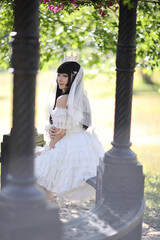 Beautiful young woman with white lolita dress with european garden Japanese fashion