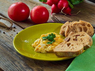 Scrambled eggs with onion and coriander served with bread on a green plate.