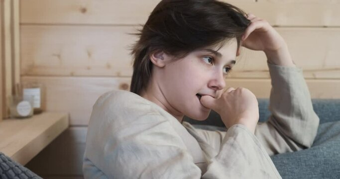 Young frustrated woman sitting on the couch, feeling despair and stress, pain and depression. Person search for a solution. Strong negative emotions. Concept of people having problem and trouble.