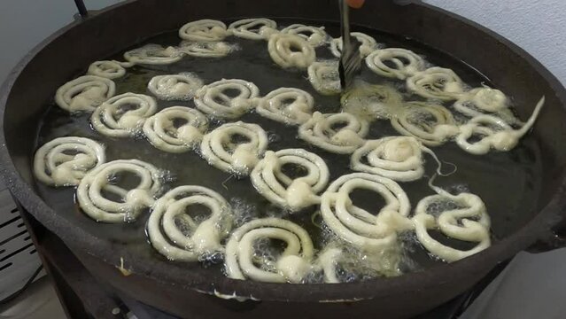 Raw jilapi deep frying 4k video clip.Jilapi making on a hot big pan.Jalebi, also known as jilapi, jilebi, jilipi, zulbia, jerry, mushabak, or zalabia, is a popular Indian sweet snack.