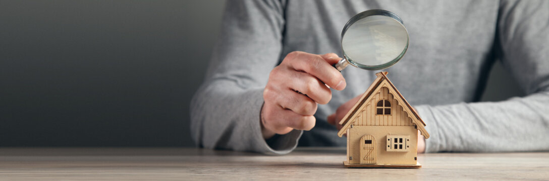 man hold magnifying glass looking house