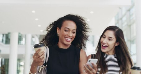 Coffee breaks are for catch ups. 4k video footage of young businesswomen chatting and using a smartphone while walking in an office on a coffee break.