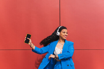Young black woman in her 20s with curly hair, wearing a 90s, 80s retro style blue outfit, dancing hip hop against a red wall, dynamic and fun expression.
