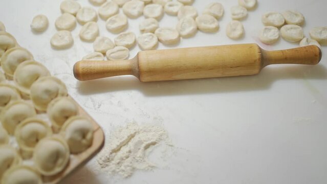 dumplings in even rows on the board and next to the rolling pin. traditional Russian cuisine. homemade dumplings