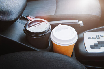 Paper coffee cup in a car. Two paper coffee cup standing inside the car between seats