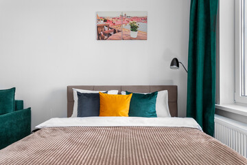 Bed with multi-colored pillows and a picture on the wall 