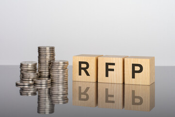 rfp - text on wooden cubes on a cold grey light background with stacks coins