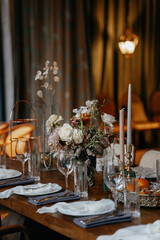 Wedding decor at the restaurant. Beautiful table setting with autumn flowers, orange and burning candles. Autumn wedding concept
