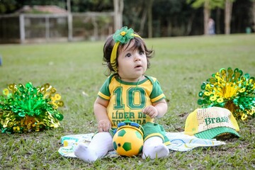 Linda criança torcedora do brasil num parque fantasiada de verde e amarelo.