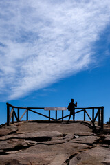 Man at a viewpoint in the mountains taking a photo with his mobile phone