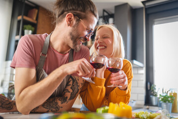 Beautiful young hipster love couple toasting with wine at home