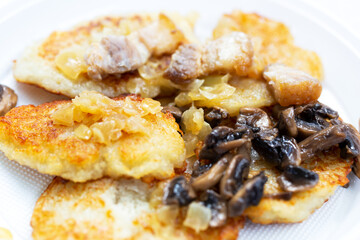 Freshly fried potato fritters with a roast of mushrooms, onions and lard
