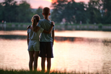 Happy siblings hugging lovingly in summer park. Young children brother and sister embracing each...