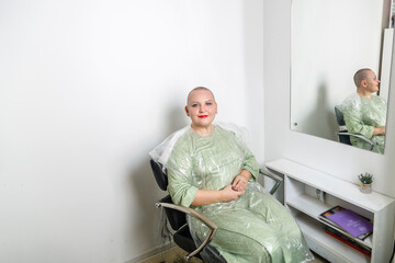 Smiling shaved bald woman in a hairdresser's chair.