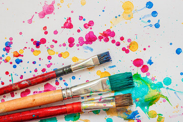 Obraz premium Artist paint brushes on background of colorful watercolor splashes, vivid blots