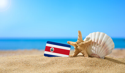 Fototapeta na wymiar Tropical beach with seashells and Costa Rica flag. The concept of a paradise vacation on the beaches of Costa Rica.